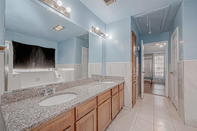 bathroom featuring tile patterned flooring, vanity, tile walls, and a textured ceiling