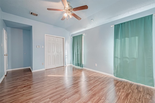 spare room with wood-type flooring, lofted ceiling, a textured ceiling, and ceiling fan