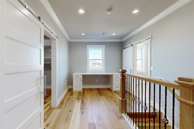 interior space featuring light wood-type flooring, a barn door, and ornamental molding