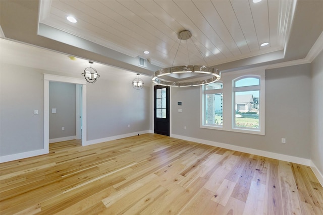 spare room featuring a raised ceiling, light wood-type flooring, crown molding, and an inviting chandelier