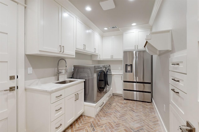 laundry area with washer and clothes dryer, sink, cabinets, and ornamental molding