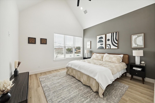 bedroom featuring light hardwood / wood-style floors, high vaulted ceiling, and ceiling fan