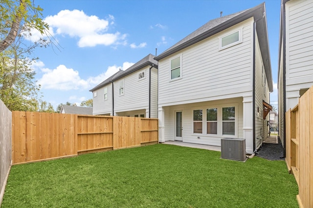 back of property with central AC unit and a lawn