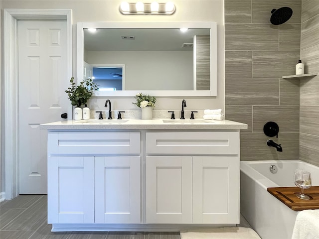 bathroom with tiled shower / bath combo and vanity