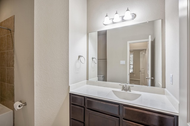 bathroom with tiled shower, vanity, and toilet