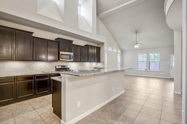 kitchen with ceiling fan, high vaulted ceiling, decorative backsplash, light tile patterned floors, and appliances with stainless steel finishes