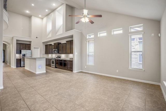 kitchen with ceiling fan, a kitchen island, high vaulted ceiling, and appliances with stainless steel finishes