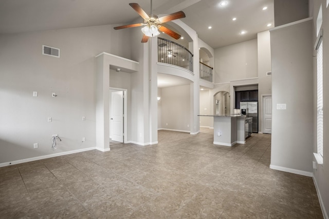 unfurnished living room with high vaulted ceiling and ceiling fan