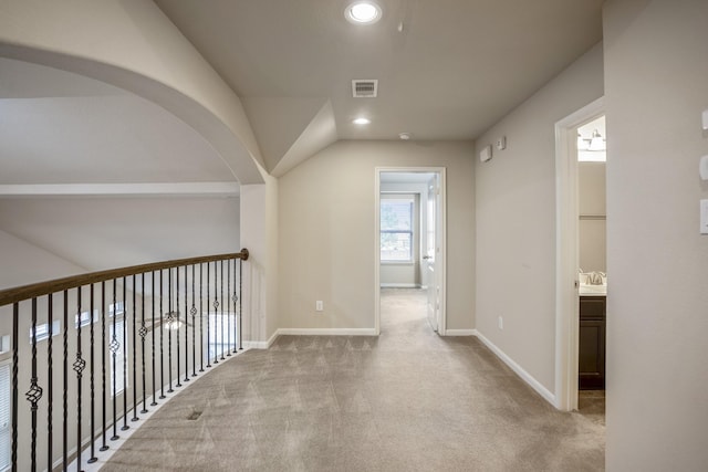 hall with light colored carpet and vaulted ceiling