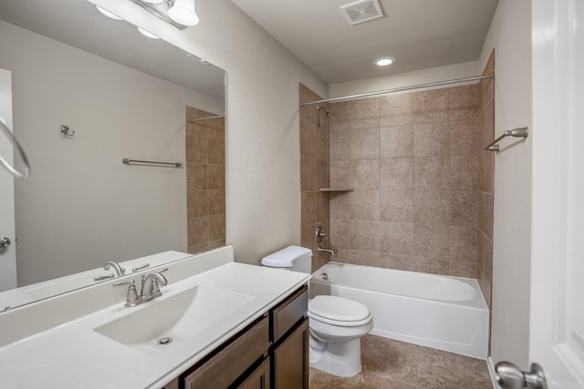 full bathroom featuring vanity, tiled shower / bath combo, and toilet