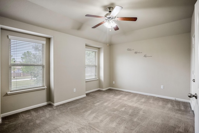 carpeted spare room featuring ceiling fan and a healthy amount of sunlight