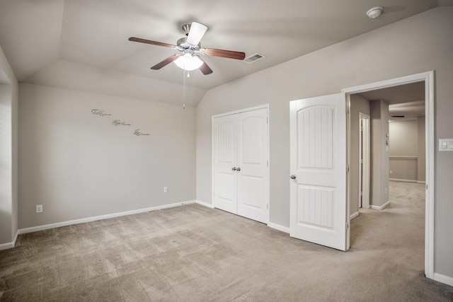 unfurnished bedroom featuring light colored carpet, vaulted ceiling, and ceiling fan