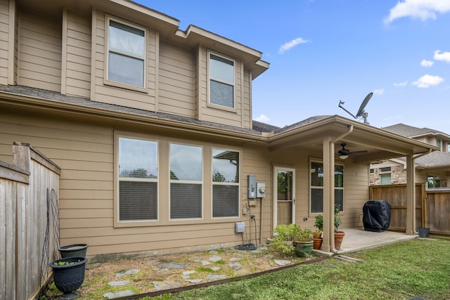 back of property with ceiling fan, a yard, and a patio