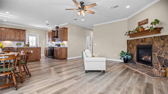 living room featuring ceiling fan, light hardwood / wood-style floors, a stone fireplace, and ornamental molding