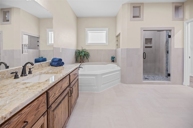 bathroom with shower with separate bathtub, vanity, tile patterned floors, and tile walls