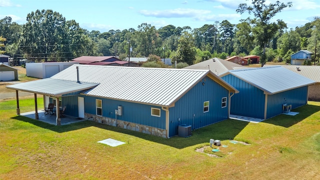 rear view of property with central AC unit, a patio area, and a yard