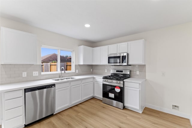 kitchen with white cabinetry, sink, appliances with stainless steel finishes, and light hardwood / wood-style flooring