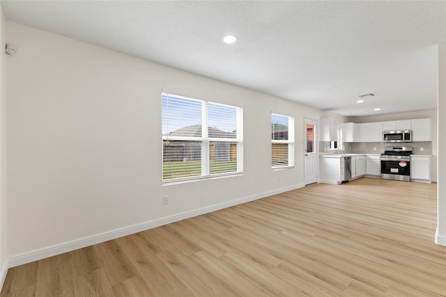 unfurnished living room with light wood-type flooring and a textured ceiling