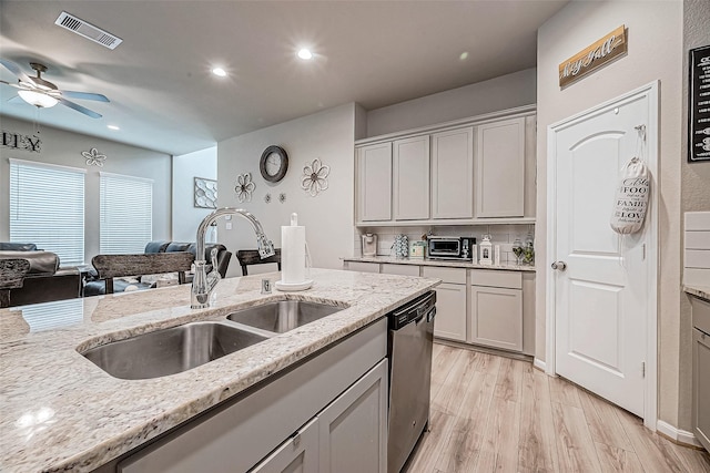 kitchen with sink, light stone counters, stainless steel dishwasher, light hardwood / wood-style floors, and gray cabinets