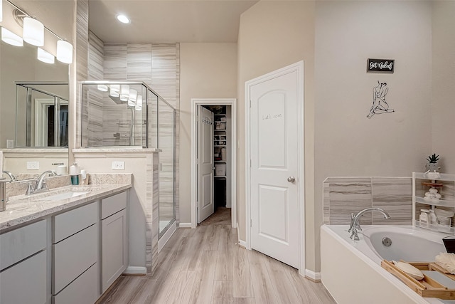 bathroom with hardwood / wood-style floors, vanity, and independent shower and bath