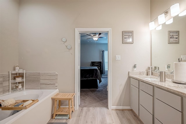 bathroom featuring a bath, ceiling fan, vanity, and wood-type flooring