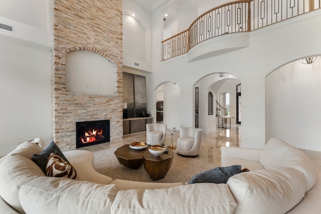 living room with a high ceiling and a stone fireplace