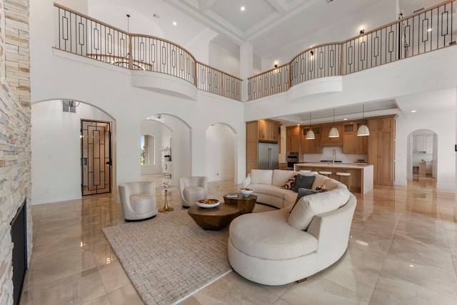 living room with a towering ceiling, sink, and a stone fireplace