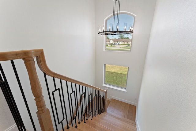 stairway with wood-type flooring and a notable chandelier