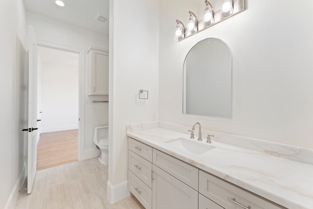 bathroom featuring toilet, vanity, and hardwood / wood-style flooring