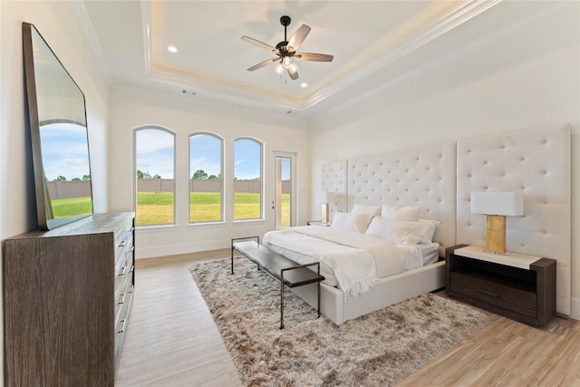 bedroom featuring ceiling fan, light hardwood / wood-style floors, a tray ceiling, and ornamental molding