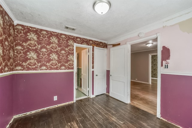 empty room with a textured ceiling, dark hardwood / wood-style floors, and ornamental molding