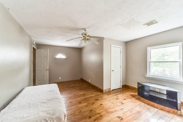 bedroom featuring ceiling fan, light wood-type flooring, and multiple windows