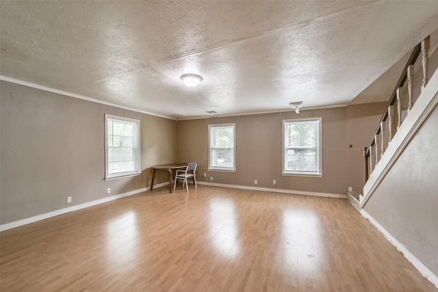 empty room with crown molding, light hardwood / wood-style flooring, and a textured ceiling