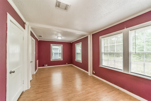 unfurnished room featuring light hardwood / wood-style floors, crown molding, and a textured ceiling