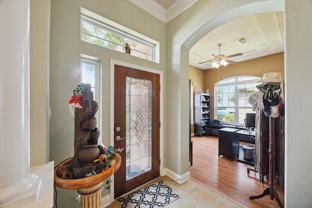 foyer with decorative columns, crown molding, a healthy amount of sunlight, and light wood-type flooring