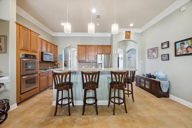 kitchen featuring a kitchen island with sink, hanging light fixtures, light stone counters, and appliances with stainless steel finishes