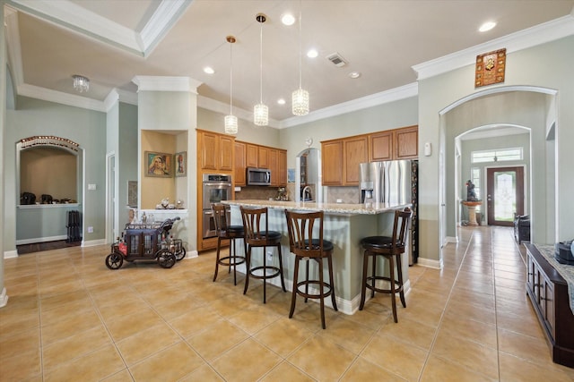 kitchen featuring crown molding, light stone countertops, stainless steel appliances, and a kitchen island with sink