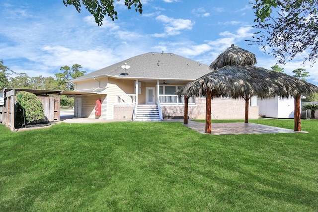 rear view of property featuring a lawn, ceiling fan, a patio, and a shed