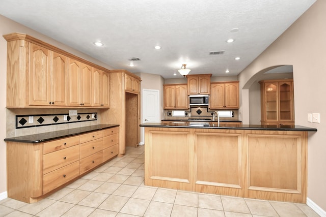 kitchen with sink, backsplash, kitchen peninsula, a textured ceiling, and light tile patterned floors