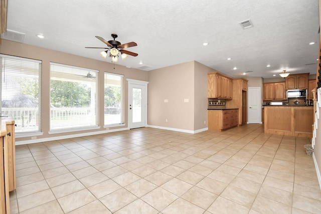 unfurnished living room with ceiling fan, light tile patterned floors, a healthy amount of sunlight, and a textured ceiling