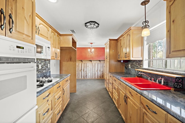 kitchen featuring pendant lighting, white appliances, dark stone counters, sink, and decorative backsplash