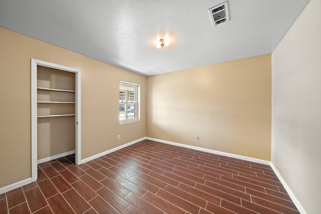 unfurnished bedroom featuring a textured ceiling, dark hardwood / wood-style flooring, and a closet