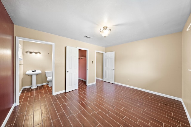 unfurnished bedroom featuring dark hardwood / wood-style floors, ensuite bath, a closet, and sink