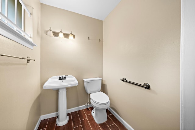 bathroom with hardwood / wood-style floors, toilet, lofted ceiling, and sink