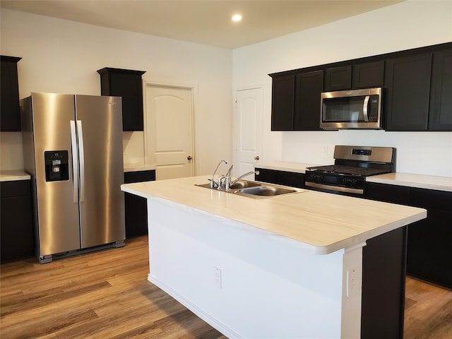 kitchen with sink, a center island with sink, stainless steel appliances, and light hardwood / wood-style floors