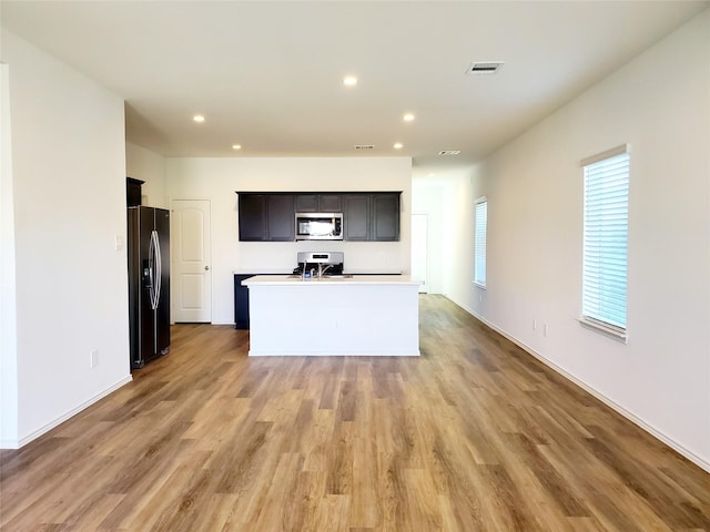 kitchen featuring a center island with sink, light wood-type flooring, and appliances with stainless steel finishes