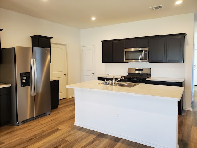 kitchen featuring sink, stainless steel appliances, a kitchen island with sink, and light hardwood / wood-style flooring