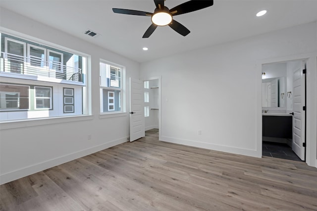 unfurnished bedroom featuring ensuite bathroom, light hardwood / wood-style flooring, and ceiling fan