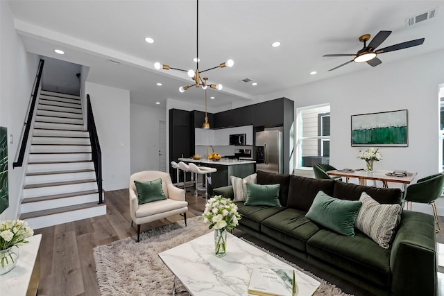 living room with dark wood-type flooring and ceiling fan with notable chandelier