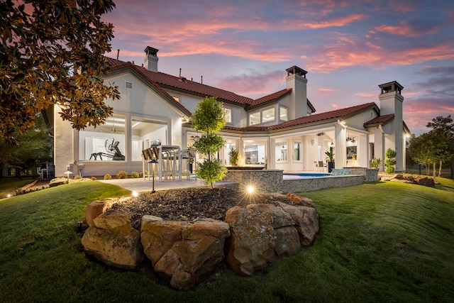 back house at dusk with a lawn